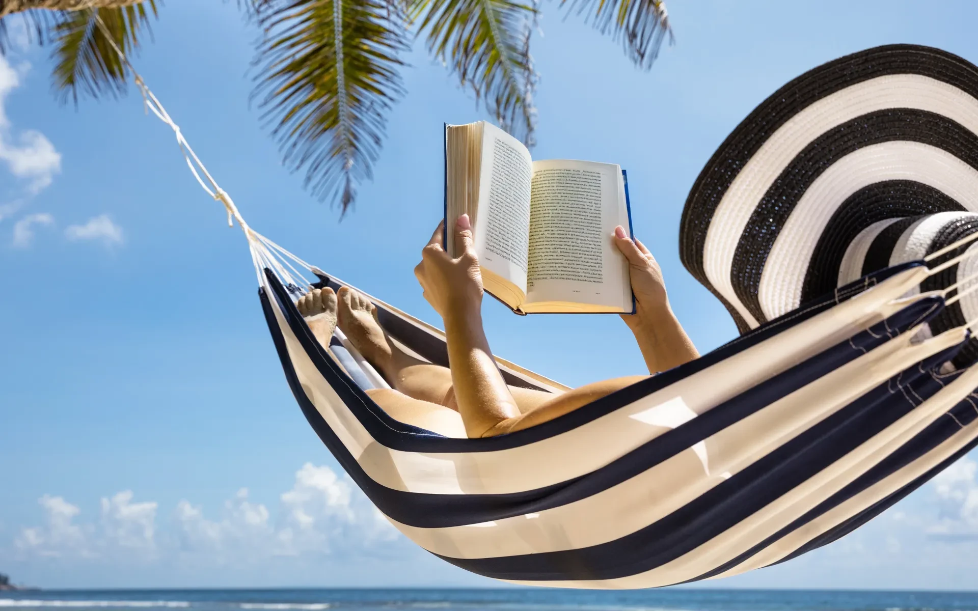 Woman reads a book in the a hammock in the Caribbean